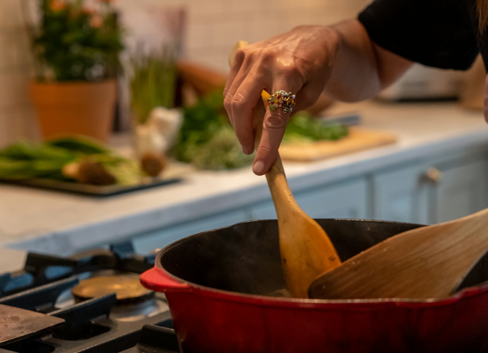 Stirring a pot of stew in a red Dutch oven